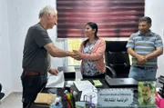 Aktivist Michael Wilk (li.) übergibt Spenden an die Stadtverwaltung Kobane für den Wiederaufbau des zerbombten Wasserwerks. Im Vordergrund ein Bild von PKK-Gründer Abdullah Öcalan.