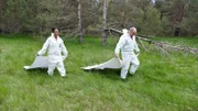 Pia und Zeckenforscher Gerhard gehen auf Zeckenjagd. Gerhard hat vorher Pias Schutzanzug zeckendicht abgeklebt.