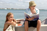 Lewis (Angus McLaren, l.) studiert ein Buch mit mystischen Seewesen, während Emma (Claire Holt) als Meerjungfrau im Meer unterwegs ist.