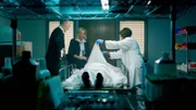 Recreation Photo – Det. Maroni, Det. Wheeler, and medical examiner examine body.