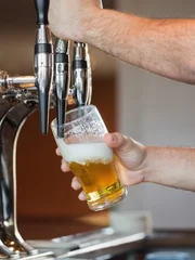 Barmans arms pulling a pint of beer behind the bar