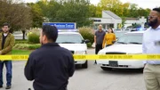 Die Polizei hat die Straße wegen der Schießerei gesperrt, Passanten beobachten das Geschehen.