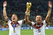 Bastian Schweinsteiger (l) und Lukas Podolski jubeln mit dem WM-Pokal nach dem Finale der Fußball-WM 2014 zwischen Deutschland und Argentinien.