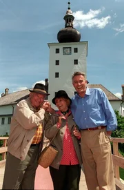 "Schlosshotel Orth", "Das Wunder von Gmunden." Wenzel Hofer und sein Team begrüßen wieder Gäste im Schlosshotel. Auch in der Familie geht es hoch her, denn Fanny heiratet heimlich Vinzenz Strobel. Fritz Havlicek, ein Pensionist aus Wien, stolpert über eine Falte im Teppich auf der Brücke. Nach dem Sturz kann er angeblich seinen Arm nicht mehr bewegen und seine Frau hofft auf ein hohes Schmerzensgeld. Im Bild (v.li.): Fritz Muliar (Fritz Havlicek), Elfriede Ott (Elfriede Havlicek), Klaus Wildbolz (Wenzel Hofer).