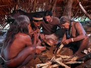 The elders show Hazen how to carve out the halves of palm wood. Once hollow, the halves are sealed together with beeswax and then wrapped in a vine.