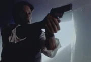 Mulder (David Duchovny) versucht, die Männer der Peacock-Familie mit seiner Waffe in Schach zu halten.