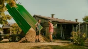 Pius (Valentin Erb, l.) verkauft BlaBla (Sebastian Jakob Doppelbauer, r.) den Sand für den Beach, während sie sich im strahlenden Sommer über das Geschäft unterhalten.