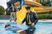 Hubert (Christian Tramitz, links) und Staller (Helmfried von Lüttichau, rechts), machen im Schwimmbad einen grausigen Fund. Auf der Wasserrutsche sitzt Bademeister Frank Brauß, erstochen! Bei dem Versuch den Toten genauer zu betrachten, rutscht Staller samt der Leiche ins Wasser.