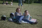 Laurent (Jonas Holdenrieder, l.) liegt gemeinsam mit Trine (Hannah Schiller, r.) auf einer Decke am Ufer des Sees.