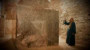 Ein Mann steht neben einer antiken Skulptur in Ägypten.