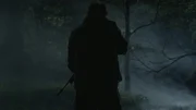 A man holds a rifle at night.