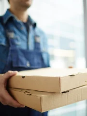 Two boxes with fast food being carried by delivery man in uniform for one of clients.