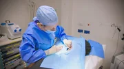 MS shot of DR Emma in scrubs performing an operation to remove Cavalli's keloids