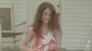 A woman with bloody hands caressing a hammer.