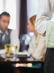 Waitress standing in front of two business people talking in a restaurant