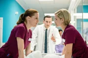 Betty (Bettina Lamprecht, l.) und Lizzy (Theresa Underberg, r.) lassen sich bei ihren Mutmaßungen über ihre Patienten nicht so einfach von AiWler Lewandowski (Eric Klotzsch, m.) unterbrechen.