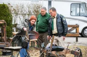 Hubert (Christian Tramitz, r.) und Girwidz (Michael Brandner, M.) wollen Jens Friedel (Sebastian Edtbauer, l.) zum Mordfall des Wurstfabrikanten befragen, doch der zeigt ihnen lieber seine Kunstwerke.