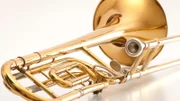 Old and used trombone on white background.