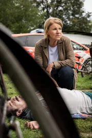 Marie Brand (Mariele Millowitsch) inspiziert am Tatort die Leiche des Platzwarts Helge Otte (Christopher Köberlein) und schaut sich um.