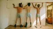 Carlo (Jeremias Meyer, M.), BlaBla (Sebastian Jakob Doppelbauer, l.) und Aydin (David Ali Rashed, r.) messen die Wand im besetzten Haus aus, während sie an der Renovierung arbeiten.