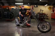 Paul Teutul, Sr. sits on a motorcycle at Orange County Choppers. (wide shot)