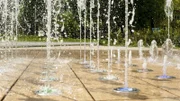 Many small splashing dancing fountains in summer Warsaw park