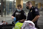 CBP-Beamter Axson schneidet ein Paket auf, das im Gepäck eines Passagiers gefunden wurde, während CBP-Aufsichtsbeamter Beran in Atlanta, Ga. zusieht (National Geographic for Disney).