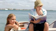 Lewis (Angus McLaren, l.) studiert ein Buch mit mystischen Seewesen, während Emma (Claire Holt, r.) als Meerjungfrau im Meer unterwegs ist.