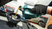 car mechanic pouring oil into motor engine