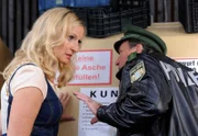 Moni Riemerschmidt (Monika Gruber) und Fred Müller (Johann Schuler) hören aus einer der Tonnen schwaches Hundegebell.