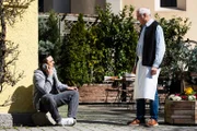 Leon (Joel Akgün) sitzt telefonierend vor dem Brunnerwirt, als Joseph (Michael Vogtmann) auf ihn zukommt.