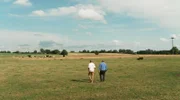 Yared und André Tamm gehen gemeinsam über die Rinderweide, um ein Kalb mit Ohrmarken zu versehen.