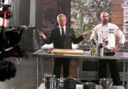 Starkoch Wolfgang Puck (l., spielt sich selbst) und Curtis LeBlanc (Matthew Holmes) stehen für die Kochshow 'Elite Chef' vor der Kamera.