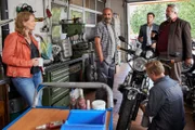 Die Kommissare Hansen (Igor Jeftic, hinter, 2.v.r.) und Stadler (Dieter Fischer, r.) befragen den Besitzer einer Motorradwerkstatt, Bernhard "Bulli" Kuhn (Hannes Ringlstätter, 2.v.l.) und seine Freundin Evi Staudinger (Stefanie von Poser, l.) zu ihrem ermordeten Freund Rocky Döbl.