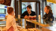 Anscheinend war nicht die Tote, sondern eine andere Frau am Morgen Brötchen holen und ist dann zum Waldhaus zurückgekehrt, um mit Kim Olemacher zu frühstücken. Paula Moorkamp (Stella Hinrichs, r.) und Austauschpolizist Eddi Jansons (Gustavs Gailus, M.) befragen deshalb die Bäckereiverkäuferin Veronika Hartmann (Lena Maria Eikenbusch, l.). Sie kann sich sogar an die Dame erinnern.