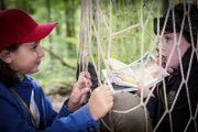 Timo (Malon Stahlhut, re.) ist in eine Netzfalle getreten – und behauptet weiterhin, im Wald gebe es Wolfsspuren. Jale (Ava Sophie Richter, li.) ist skeptisch.