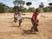 Hazen Audel carrying a log with the help of three Samburu warriors in the Kenyan bush.