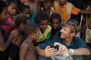 PAPUA NEW GUINEA- Production assistant Stuart Trowell shows some iPhone pictures to the local kids.