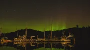 The northern lights reflect off the boats along the docks of Port Protection.