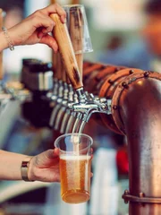 Beer tapping with traditional taps into a plastic cup and colorful blurred background