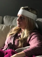 Dana sitting on the couch after having brain surgery.
