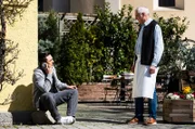 Leon (Joel Akgün) sitzt telefonierend vor dem Brunnerwirt, als Joseph (Michael Vogtmann) auf ihn zukommt.