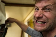 Shawn Pomrenke bares his teeth, aggressively scooping gold into a large sluice.