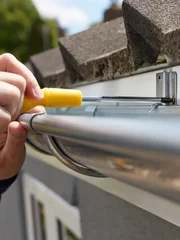 Close Up Of Man Replacing Guttering On Exterior Of House