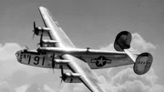 Heldenszene eines B-24 Liberators im Flug von Maxwell Field, Alabama, einer Pilotschule für viermotorige Flugzeuge, glänzt in der Sonne, während er in großer Höhe in den Wolken eine Kurve fliegt.