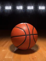 A basketball on a wood floor beneath bright arena lights