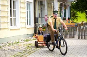 Riedl (Paul Sedlmeir, r.) bemerkt nicht, dass er aussieht wie ein Clown und macht sich mit Lina (Carla Graßl, l.) im Bollerwagen auf den Weg zum Revier.