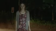 A girl staring into the headlights of a car, crying.