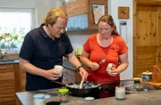 Verena Sommerfeld  zeigt Björn Freitag (l), wie sie ihr köstliches Griebenschmalz herstellt.