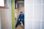 Ein Toter (Komparse) liegt in einer der Toilettenkabinen.